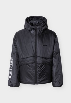 Must kapuutsiga puffer-jope eesluku, rinnal "HUGO" logo ja vasakul varrukal "PERTEX" kiri, valgel taustal eksponeeritud.