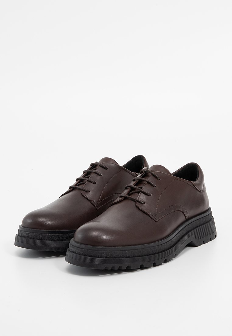 Brązowe skórzane buty na sznurówki o gładkiej fakturze, z piętą w kolorze czarnym, zaokrąglonym noskiem i subtelnym przeszyciem wzdłuż boków.