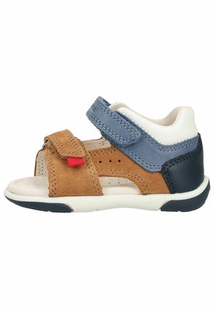 Børnesandal med brune, blå, hvide og sorte ruskind- og læderdelssektioner, åben tå og to justerbare velcroremme.