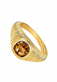 Anillo dorado con un diseño acanalado torcido que presenta una gran gema de ámbar en corte cuadrado, mostrando un intrincado facetado y superficies reflectantes.