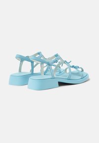 Light blue block-heel sandals with a strappy design, featuring adjustable ankle straps and a smooth texture.