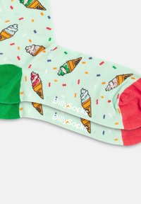 Lichtgroene sokken met een ijsje patroon, voorzien van rode en groene accenten. Zacht materiaal met verspreide kleurrijke sprinkles. Merkennaam zichtbaar.