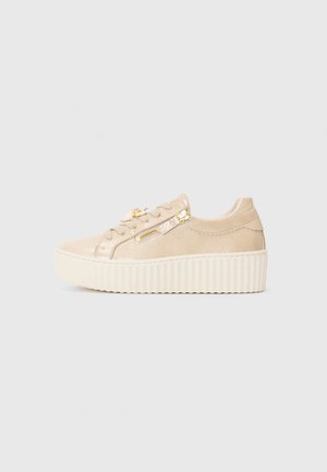 Beige suede sneaker with a thick cream platform sole, featuring metallic accents and decorative zipper detail on the side.