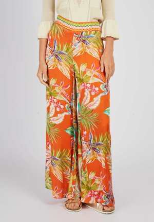 Szerokie spodnie wykonane z intensywnego pomarańczowego materiału, zdobione kwiatowym wzorem z zielonymi liśćmi i niebieskimi kwiatami. Wykończone paskiem w zygzakowaty wzór.