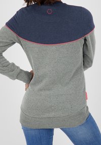 Gray sweatshirt with a navy upper section, featuring pink piping. Made from soft fabric with ribbed cuffs and hem. Accented logo on back.