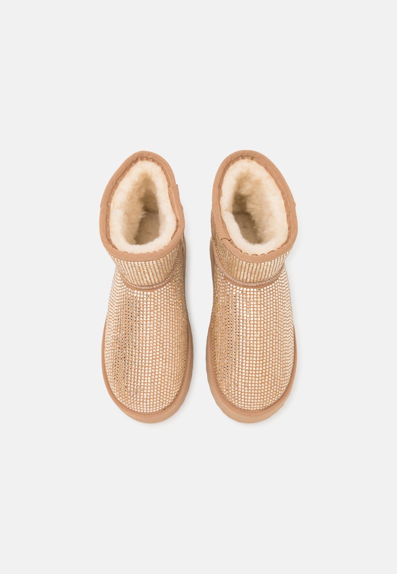 Tannfarbene Stiefeletten mit einem strukturierten Mesh-Obermaterial und weicher Fellinnenausstattung. Sie verfügen über eine runde Zehe, eine Gummisohle und einen verstellbaren Riemen in der Nähe des Knöchels.