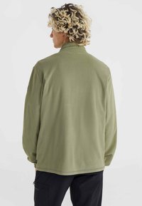Olive green fleece jacket with a stand-up collar, long sleeves, and a straight hem. Features subtle stitching and logo details on the collar.