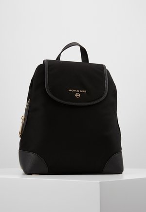 Black nylon backpack with a flap closure, gold hardware, and leather accents at the base. Features a front zip pocket and adjustable straps.