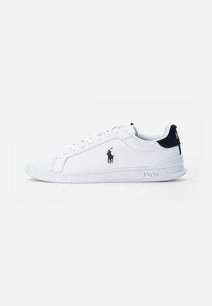 Weißer flacher Sneaker mit schwarzem Polo Ralph Lauren Logo an der Seite, schwarzer Fersenlasche und weißer Sohle mit "Polo" Prägung nahe der Ferse.
