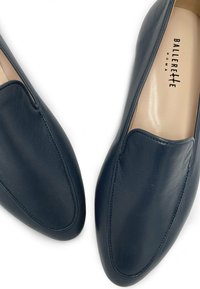 Mocassini in pelle blu navy con texture liscia, caratterizzati da un design elegante, forma aderente e dettagli di cucitura discreti. Logo visibile sulla soletta.