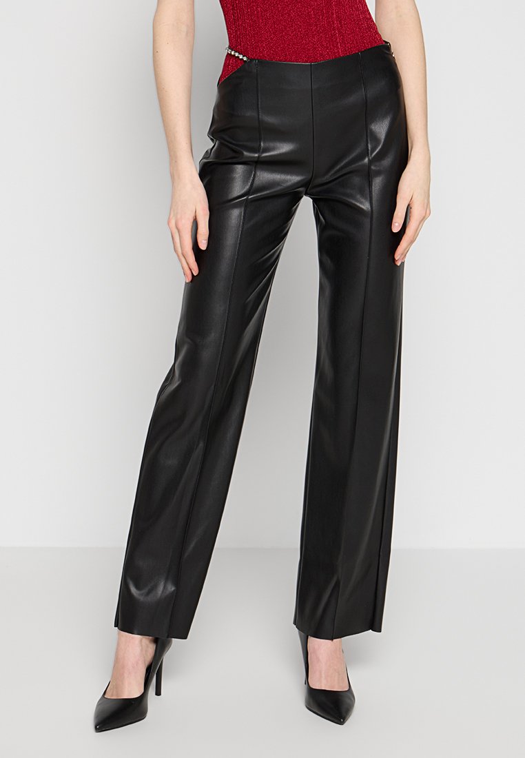 Zwarte faux leer broek met een recht pasvorm, voorzien van subtiele zijzakken en een zachte textuur. Accentuated met een metalen kettingdetail.