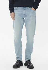 Šviesiai mėlyni džinsai, tiesaus silueto, penkių kišenių stilius, derinami su juodais raišteliais bateliais, lygus paviršius, minimaliai pažeisti.