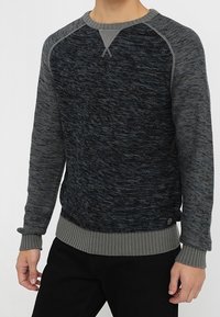 Pullover mit strukturiertem dunkelgrauem Oberteil, kontrastierendem geripptem grauem unteren Bund und Bündchen, Rundhalsausschnitt und Raglanärmeln.