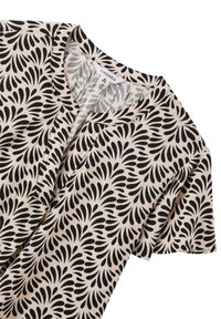Blusa beige a maniche corte con motivo astratto a foglia nera, scollo rotondo e etichetta frontale che mostra la taglia XXL e il marchio Terranova.