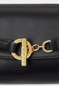 Μαύρη δερμάτινη τσάντα χειρός με λεία υφή, χρυσά αξεσουάρ, οβάλ κούμπωμα και αλυσίδα με ραφή στην κορυφή.