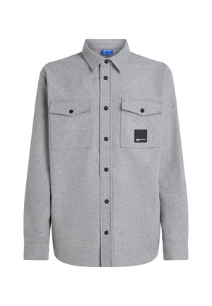Camisa de franela gris de manga larga, con botones en la parte delantera, dos bolsillos en el pecho y un parche de logo negro. Presenta botones negros y un cuello clásico.
