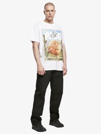 T-shirt graphique blanc avec un design de basket-ball coloré, associé à un pantalon noir et des chaussures noires. Style simple, coupe décontractée, manches courtes.