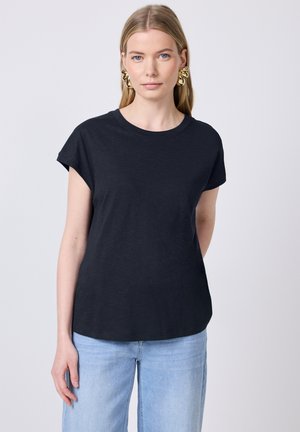 T-shirt nera a maniche corte con scollo rotondo, realizzata in tessuto morbido, abbinata a jeans a gamba larga di colore blu chiaro.