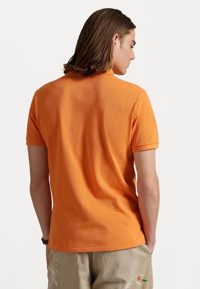 Korte mouwen polo in feloranje katoen met een gestructureerde afwerking, voorzien van een klassieke kraag en een rechte zoom.