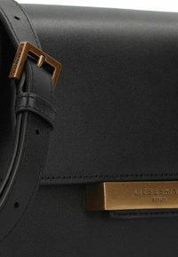 Black leather handbag featuring a sleek design, a gold metal buckle, and a metallic accent with embossed brand name.