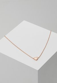Roségoldene Halskette mit einer zarten Kette und einem kleinen Herzanhänger. Der Anhänger hat eine glatte, reflektierende Oberfläche.