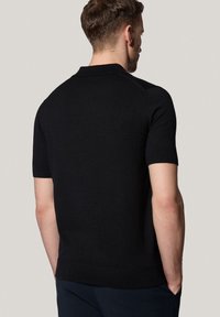 Czarna, krótko-sleeve polo wykonana z dzianiny, z prążkowanym kołnierzykiem i dołem, gładka tekstura, prosty design bez wzorów.