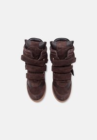 Ζευγάρι σκούρα καφέ σουέντ ψηλά αθλητικά παπούτσια με τρεις λουρίδες βέλκρο και επενδεδυμένες περιμέτρους, απεικονιζόμενα από πάνω σε λευκό φόντο.