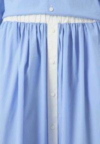 Vestido a rayas azul claro y blanco con cierre de botones en la parte delantera y cintura fruncida, con una textura suave y una tela blanda.