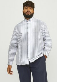 Striped button-up shirt with long sleeves, featuring vertical navy stripes on a white base, soft fabric, and a single chest pocket.