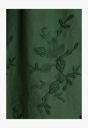 Dunkelgrüner Stoff mit filigraner Stickerei von Blättern und Zweigen in passendem Garn. Glatte Textur mit mattem Finish.