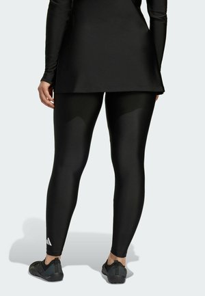 Sorte atletiske leggings lavet af glat, strækbart materiale, parret med en matchende langærmet bluse. Har et subtilt brandlogo på benet.