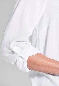 Weißes Hemdsärmel mit einem geknöpften Manschette, aus glattem, leicht durchsichtigem Stoff und einem hochgerollten Design.