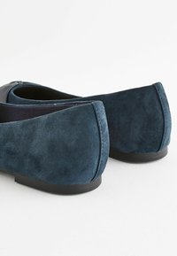 Bailarinas de ante azul marino con punta redondeada suave, costuras sutiles y suela de goma baja, diseñadas para un ajuste cómodo.
