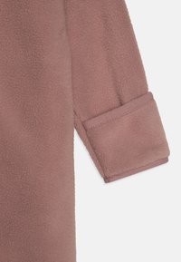 Maniche in fleece di colore rosa polveroso, con superficie texturizzata e polsino ripiegato con bordo liscio.