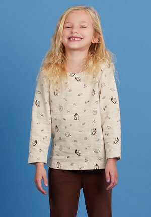 Beige overhemd met lange mouwen en bedrukte dieren- en natuurmotieven in bruin. Zachte stof, ronde halslijn, gecombineerd met bruine textuurbroek.