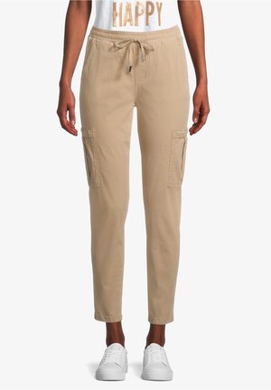 Mujer con pantalones jogger cargo beige con cintura de cordón y zapatillas blancas, combinados con una camiseta blanca que dice "HAPPY".