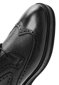 Schwarze Lederhalbschuhe mit strukturiertem Finish und glatter Zehenpartie. Verfügt über dekorative Broguedetails und eine robuste Sohle.