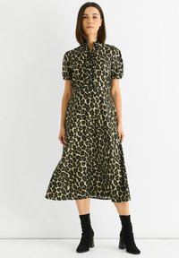 Leopard print dress in beige and black, featuring short puff sleeves and a ruffled neckline. Worn with black heeled ankle boots.