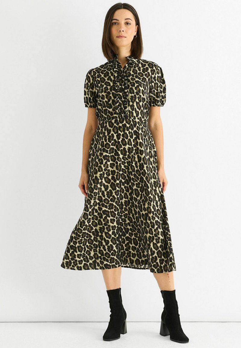 Leopard print dress in beige and black, featuring short puff sleeves and a ruffled neckline. Worn with black heeled ankle boots.