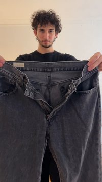 Svarte denimjeans med glidelås og knapp, samt forhåndslommer. Stoffet har en falmet tekstur med subtile variasjoner.