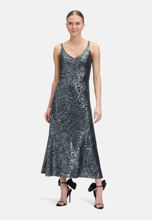 Paillettenbesetztes, dunkel tealfarbenes Kleid mit V-Ausschnitt und verstellbaren Trägern, das eine ausgestellte Silhouette aufweist. Schwarze High Heels mit Schleifenakzenten.