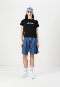 Černé tričko s bílým logem "Carhartt", modré denimové kraťasy, bílé tenisky a světle modrá kšiltovka. Oblečení má pohodlný střih.