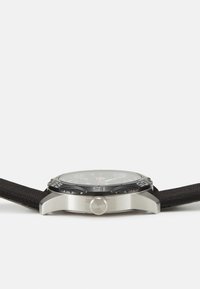 Reloj analógico negro con caja de acero inoxidable, correa de tela texturizada y una cara clara con marcadores de horas rojos y blancos y una corona.