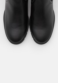 Mustat nahka nilkkurit, joissa on sileä pinta, pyöristetty kärki ja matala kumipohja. Ei näkyviä kiinnityksiä tai lisäkoristeita.