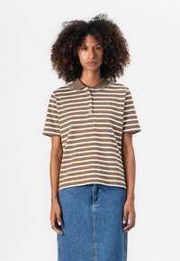 Brun og hvit stripete polo-skjorte med krage, med en tre-knappslukking og en liten logo på brystet. Båret med et denim-skjørt.