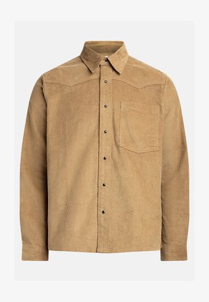 Tan corduroy shirt with a button-down collar, long sleeves, and a chest pocket. Features vertical ribbed texture and black buttons.
