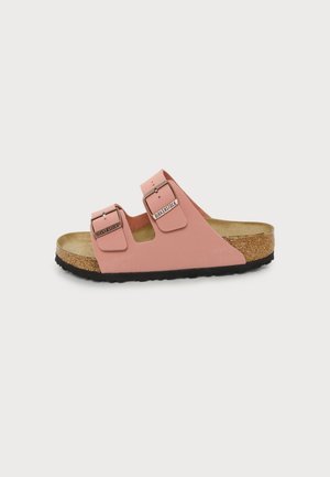 Różowa sandał Birkenstock z dwoma regulowanymi paskami z klamrami, korkową wkładką i czarną teksturowaną podeszwą, widoczna z boku na białym tle.