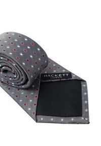 Cravatta grigia con pois rossi e blu, realizzata in tessuto liscio, arrotolata con un lato inferiore nero uniforme. Marchio Hackett London visibile.