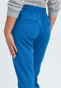 Blaue Sporthosen mit elastischem Bund, glatter Textur und zwei hinteren Taschen. Das Design zeichnet sich durch eine taillierte Silhouette aus.