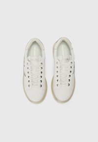 Zapatillas blancas con un acabado texturizado, que presentan acentos metálicos plateados, puntera redonda y cordones plateados en la parte delantera.